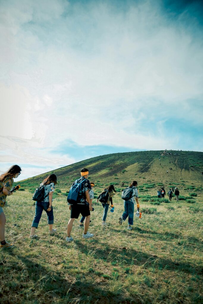 A group of hikers ascending a scenic hillside under a bright blue sky, perfect for adventure and travel themes.
